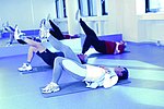 Stilisiertes Pressebild 1 (Ein bläulich gefärbtes Bild, welches ein Gruppentraining darstellt. Der helle Trainingsraum enthält 3 am Boden liegende Trainierende auf Yoga-Matten mit rechts gehobenem Bein.)